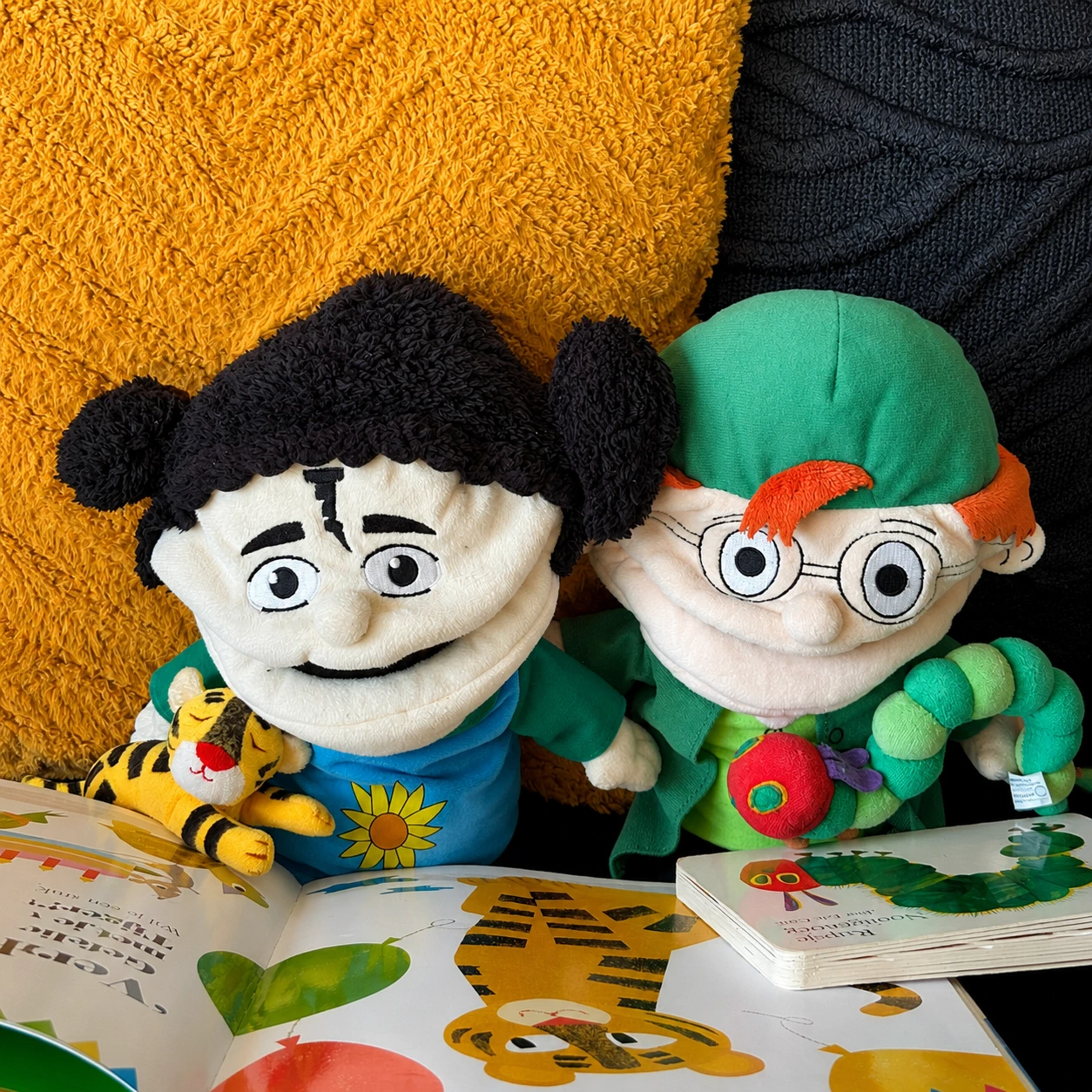 Foto in de woonkamer boeken voorlezen met bijpassend knuffeltje met de handpoppen van de methode.