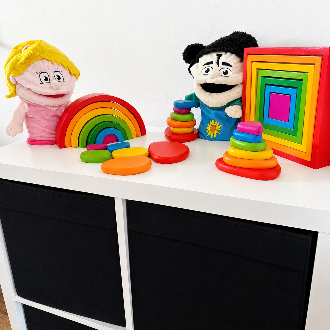 Foto in de woonkamer van het houten speelgoed met de handpoppen van de methode.